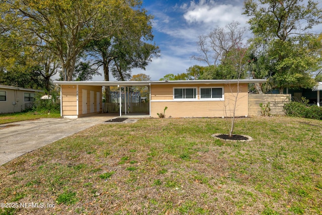 ranch-style home with concrete driveway, an attached carport, a front lawn, and fence