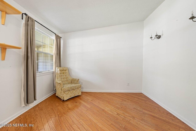 unfurnished room with baseboards, a textured ceiling, and light wood finished floors