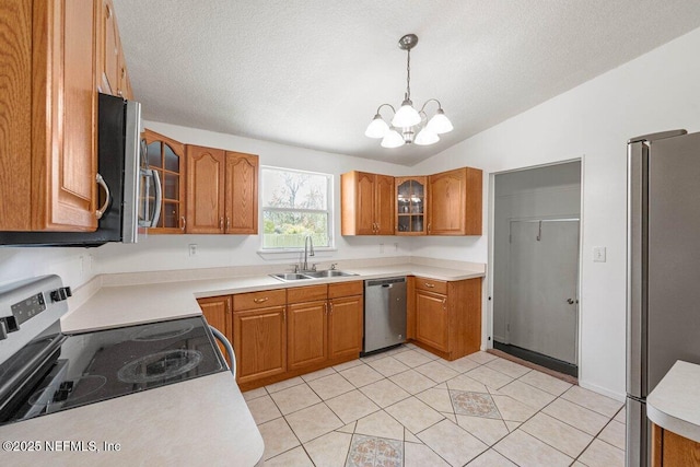 kitchen with a sink, vaulted ceiling, appliances with stainless steel finishes, brown cabinets, and a chandelier