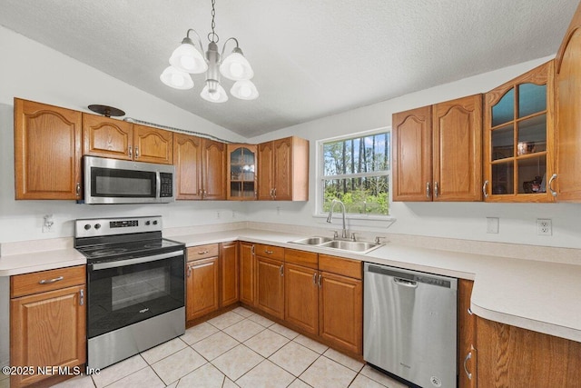 kitchen with a sink, a notable chandelier, appliances with stainless steel finishes, and brown cabinetry