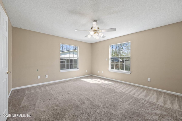 spare room featuring carpet flooring, a healthy amount of sunlight, baseboards, and a ceiling fan