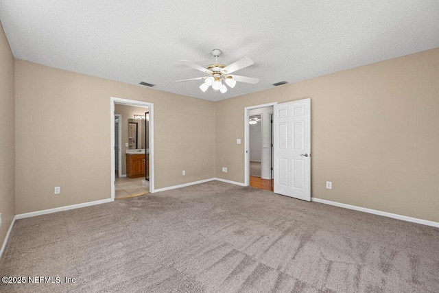 unfurnished bedroom featuring visible vents, baseboards, light colored carpet, and a textured ceiling