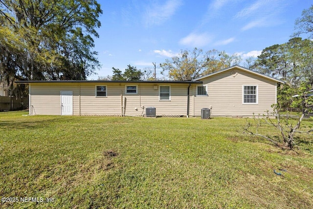 rear view of property with central air condition unit, a yard, and fence