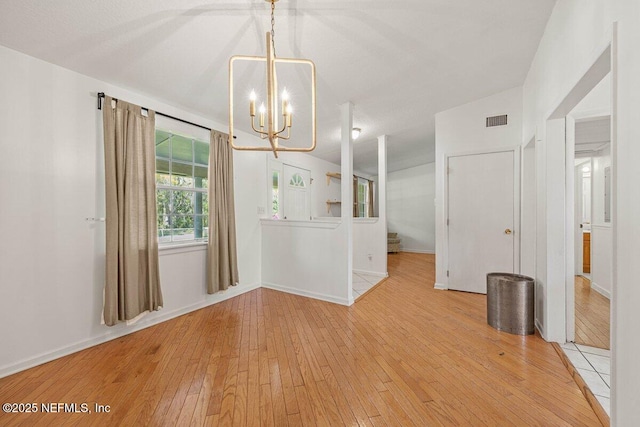 unfurnished dining area featuring a chandelier, visible vents, light wood finished floors, and baseboards