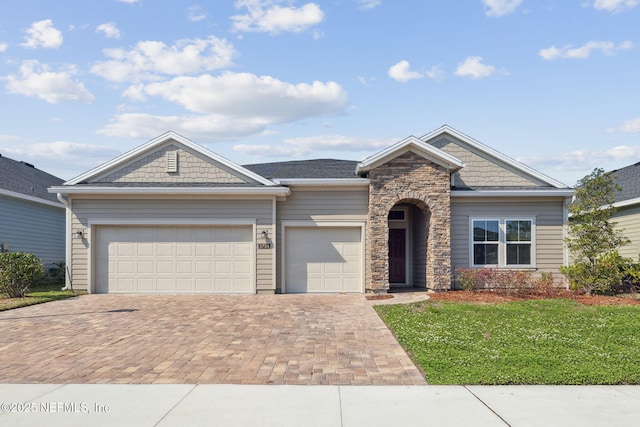 view of front of home with a garage, stone siding, a front lawn, and decorative driveway