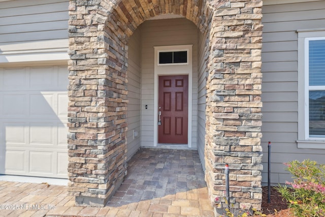 doorway to property featuring a garage and stone siding