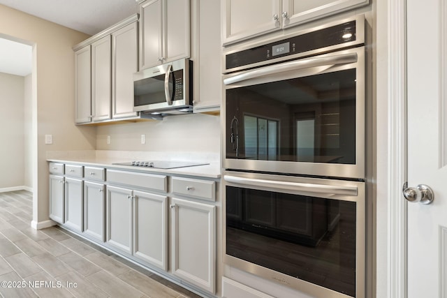 kitchen featuring appliances with stainless steel finishes, wood tiled floor, light countertops, and baseboards