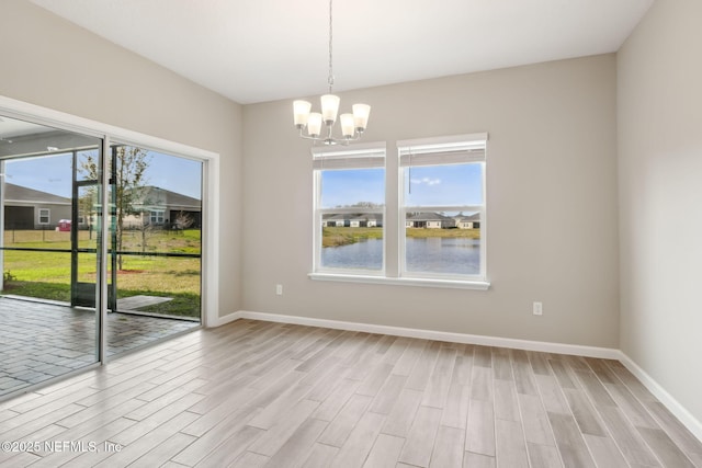 unfurnished dining area with light wood-style floors, baseboards, and a chandelier