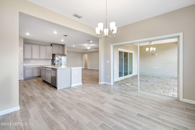 kitchen featuring open floor plan, stainless steel appliances, light countertops, gray cabinetry, and a chandelier