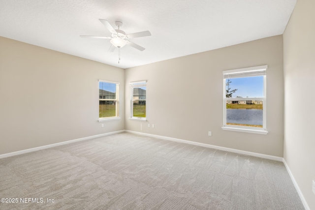 carpeted spare room featuring a ceiling fan, a wealth of natural light, and baseboards