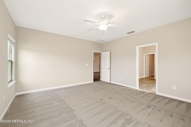 spare room with carpet floors, visible vents, ceiling fan, and baseboards