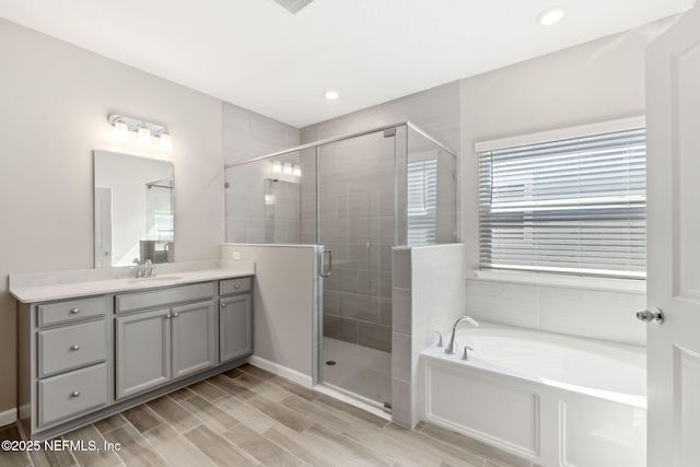 bathroom with a garden tub, a shower stall, and vanity