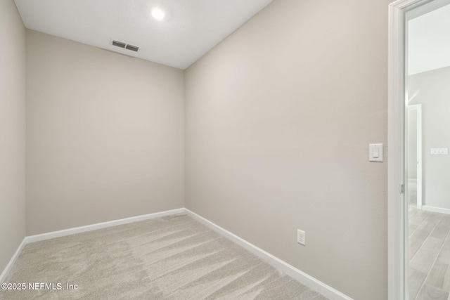 empty room featuring light colored carpet, visible vents, and baseboards