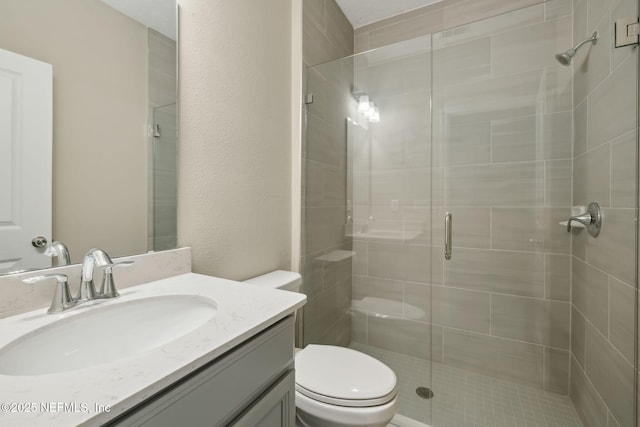 full bathroom featuring a stall shower, vanity, and toilet