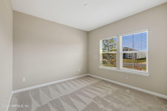 unfurnished room with baseboards and light colored carpet