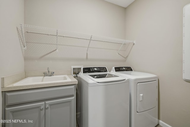 clothes washing area with cabinet space, washer and dryer, and a sink