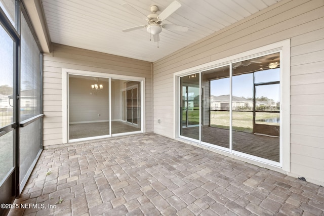 unfurnished sunroom with ceiling fan with notable chandelier