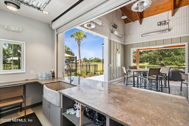 kitchen with open shelves, stone counters, and a sink