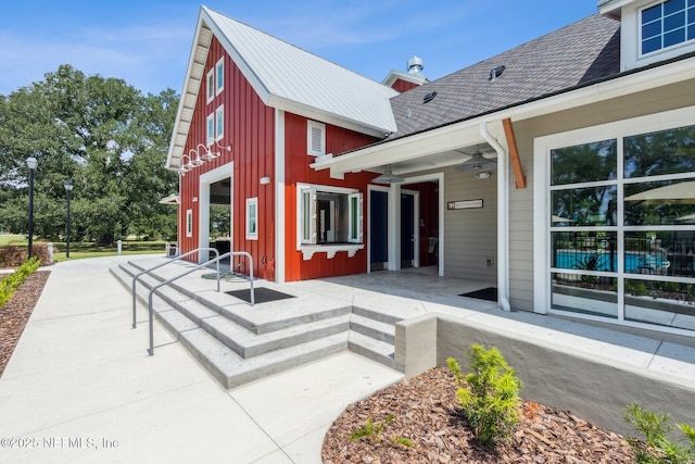 exterior space with ceiling fan, roof with shingles, and board and batten siding