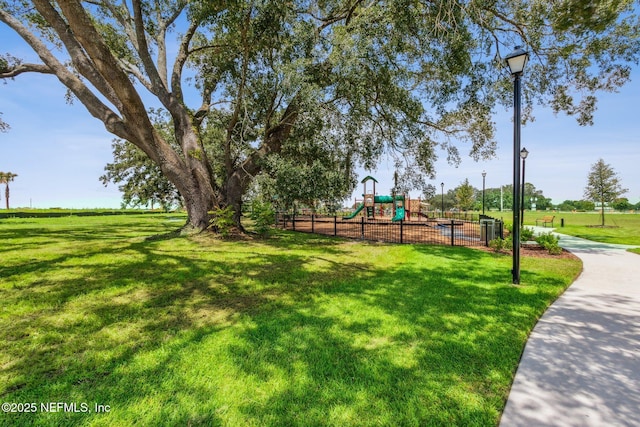 surrounding community with fence, a lawn, and playground community