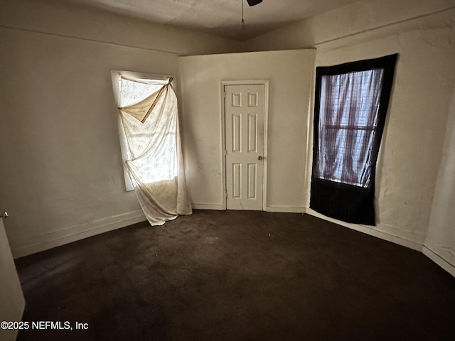 unfurnished bedroom with dark carpet and baseboards