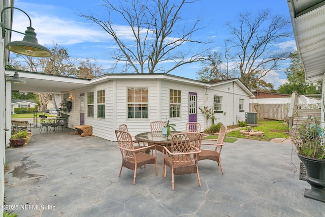 view of patio featuring fence, central AC unit, a carport, and outdoor dining space