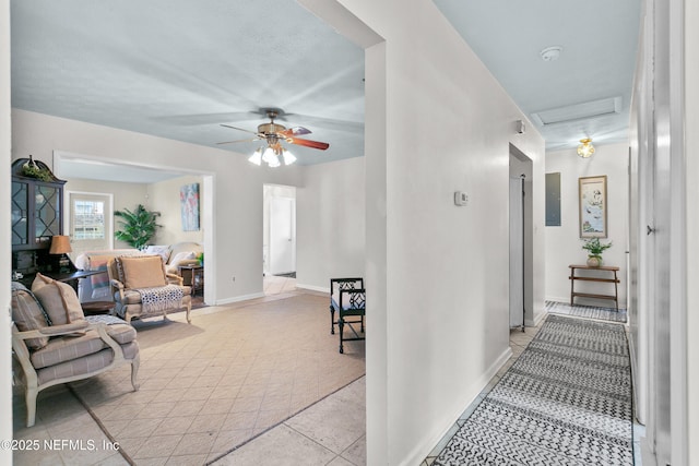 hall featuring attic access, electric panel, and baseboards