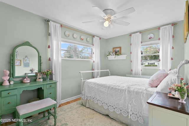 bedroom featuring a ceiling fan, multiple windows, and baseboards