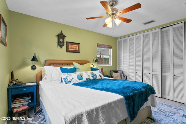 tiled bedroom featuring a ceiling fan, visible vents, and a closet