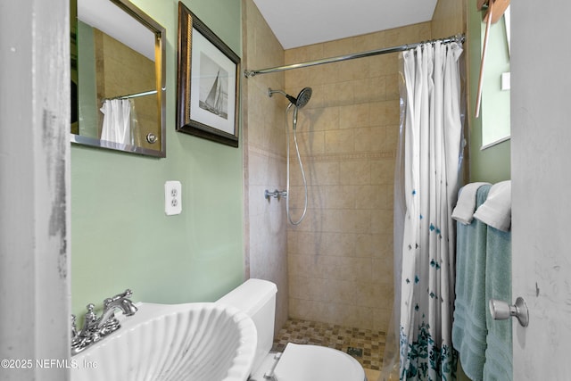 full bath featuring tiled shower, a sink, and toilet