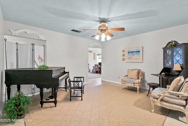 sitting room featuring arched walkways, ceiling fan, visible vents, and baseboards