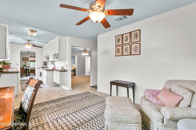 living area with light tile patterned floors, ceiling fan, and visible vents