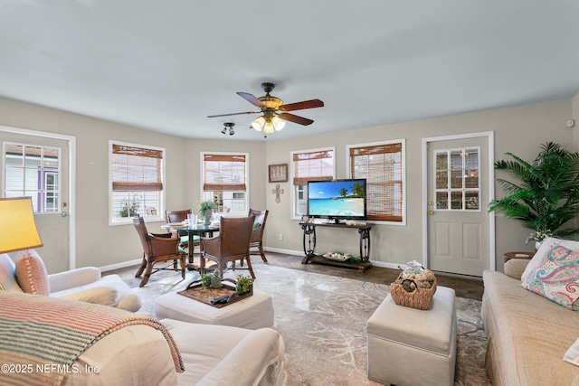 living area featuring a ceiling fan and baseboards