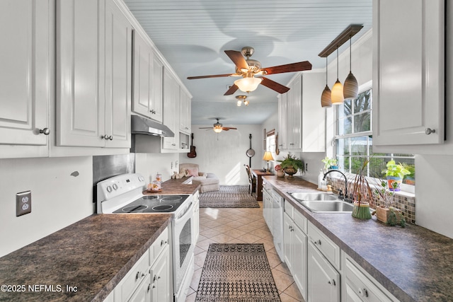 kitchen featuring light tile patterned floors, under cabinet range hood, white appliances, a sink, and dark countertops