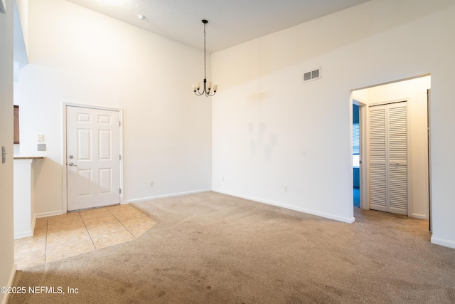 4908 Key Lime Dr Unit 301, Jacksonville, FL 32256 - empty room featuring visible vents, a notable chandelier, carpet, a high ceiling, and tile patterned flooring