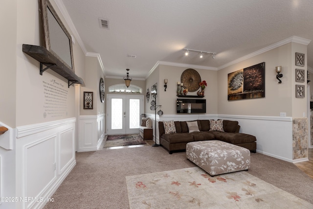 living room featuring carpet floors, french doors, visible vents, and a wainscoted wall