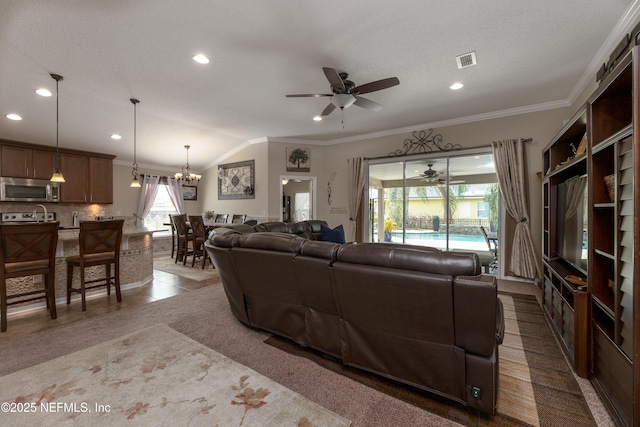 tiled living room with ceiling fan with notable chandelier, visible vents, and ornamental molding