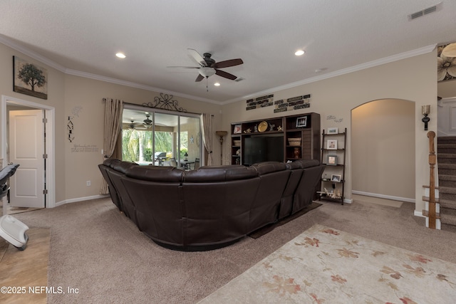 living room with ornamental molding, arched walkways, visible vents, and stairway