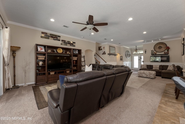 living room featuring visible vents, arched walkways, a textured ceiling, and ornamental molding