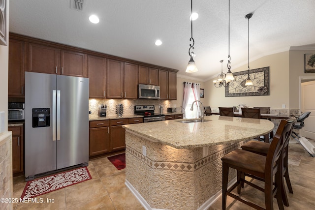 kitchen with lofted ceiling, visible vents, appliances with stainless steel finishes, ornamental molding, and a sink