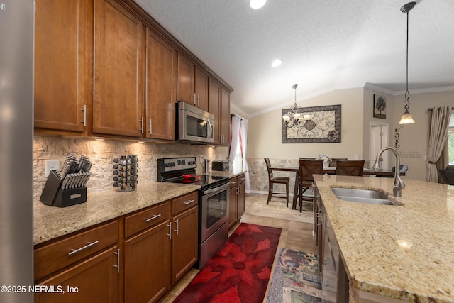 kitchen featuring light stone counters, crown molding, appliances with stainless steel finishes, vaulted ceiling, and a sink