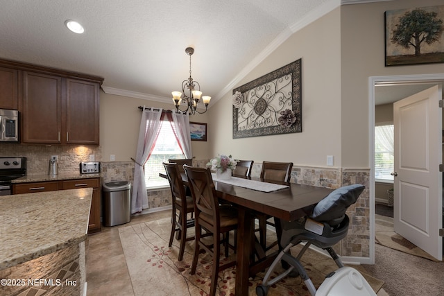 dining space featuring ornamental molding, wainscoting, vaulted ceiling, and a notable chandelier