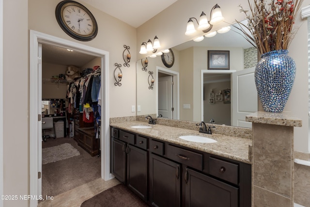 full bathroom featuring double vanity, a walk in closet, and a sink