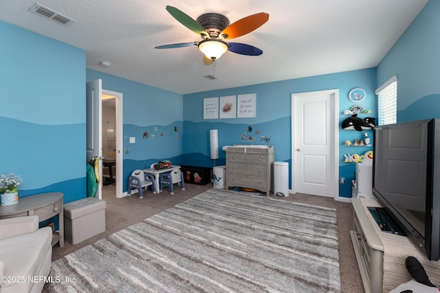 bedroom with a textured ceiling, carpet, visible vents, and a ceiling fan