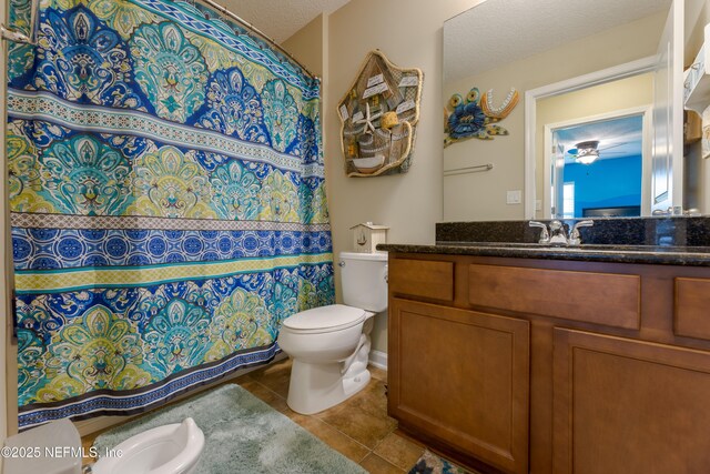 bathroom with a textured ceiling, curtained shower, vanity, and toilet