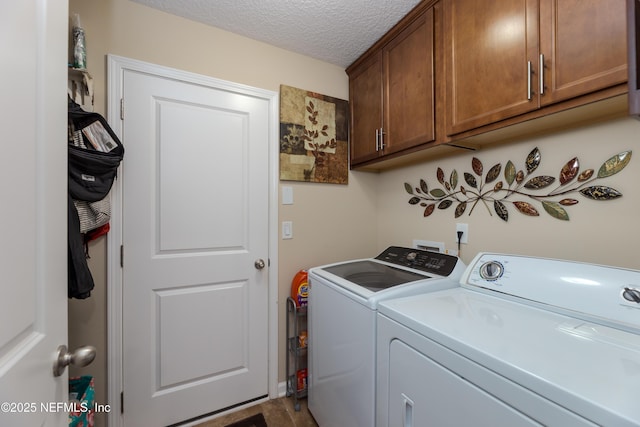 washroom with a textured ceiling, washer and clothes dryer, and cabinet space