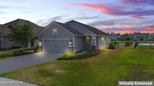 view of front facade with a garage, fence, driveway, stone siding, and a front yard