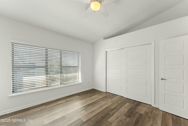 unfurnished bedroom featuring ceiling fan, dark wood finished floors, vaulted ceiling, and a closet