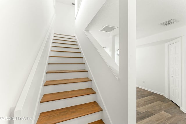 stairway featuring visible vents and wood finished floors