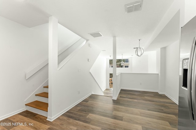 interior space featuring visible vents, stairway, wood finished floors, a chandelier, and baseboards